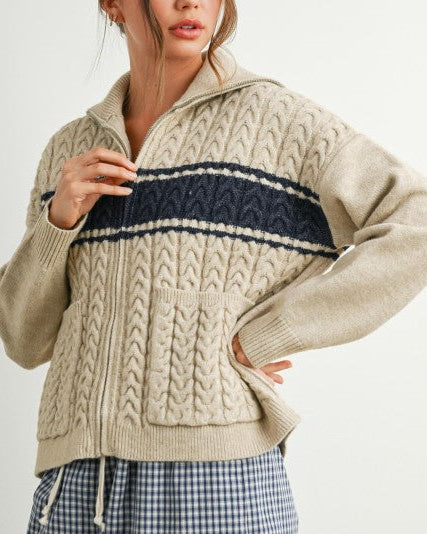 Woman wearing a beige sweater with a navy stripe on a white background