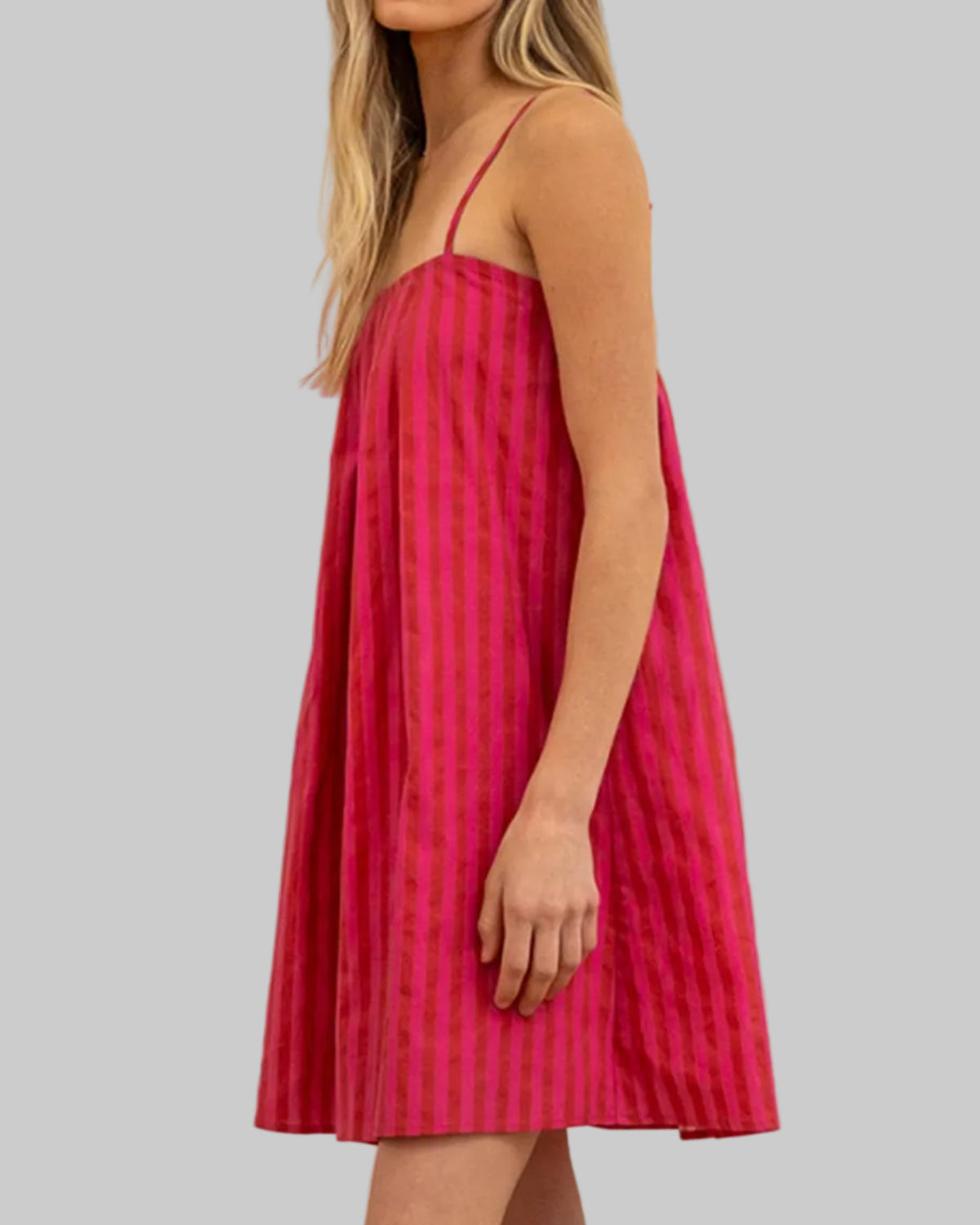 Woman wearing a pink dress with a subtle pattern in an indoor setting.