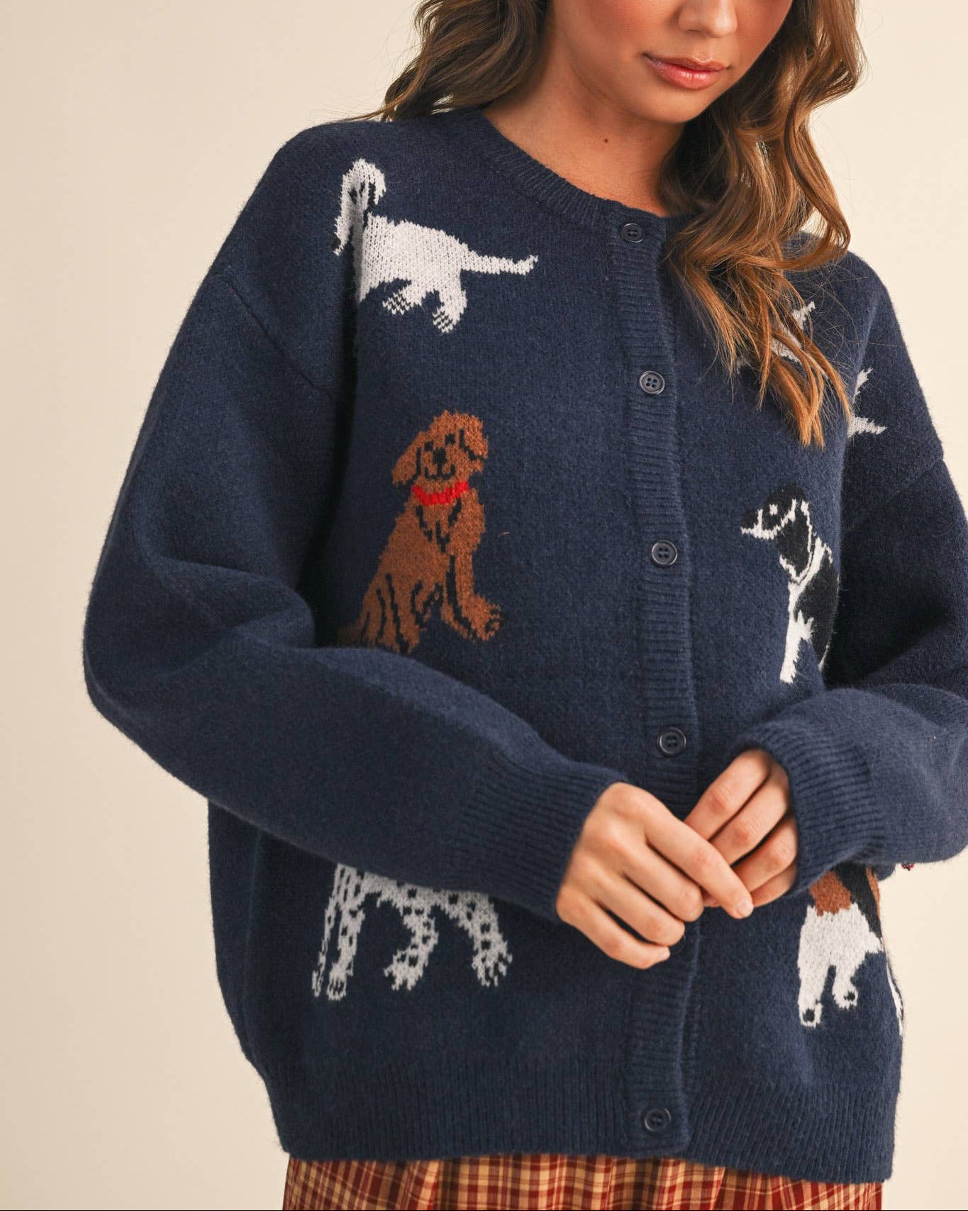 Woman wearing a navy blue cardigan with dog illustrations on a beige background