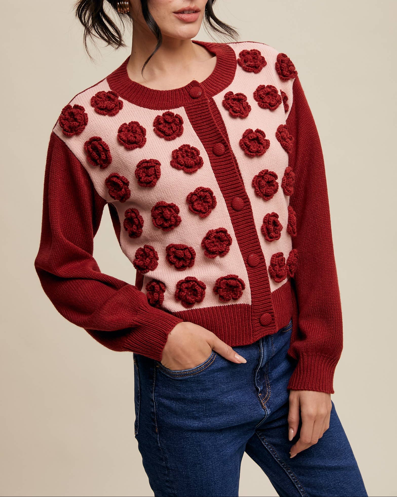 Woman wearing a red and pink cardigan with floral patterns on a beige background