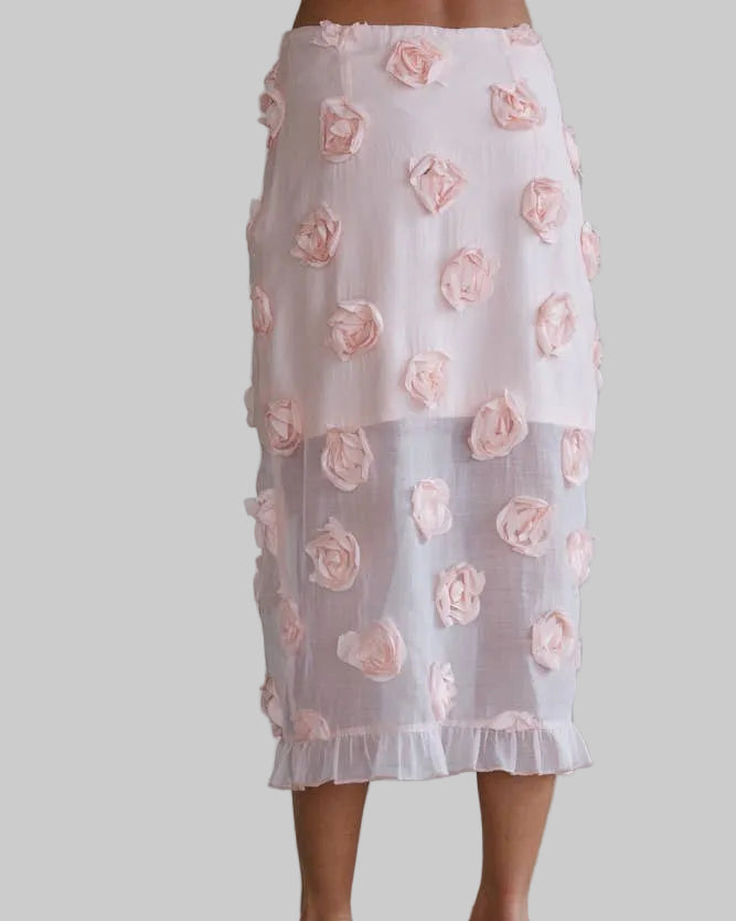 White skirt with pink floral patterns worn by a person against a plain background