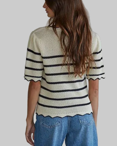 Woman wearing a striped sweater and blue jeans against a plain background