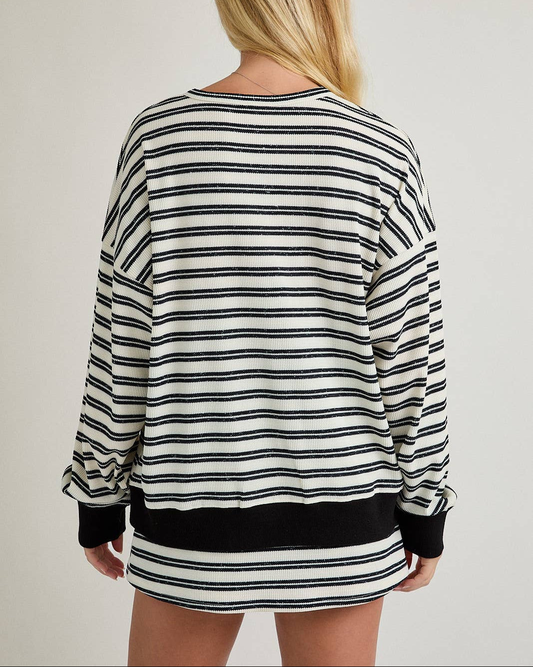 Person wearing a black and white striped sweater with a plain background