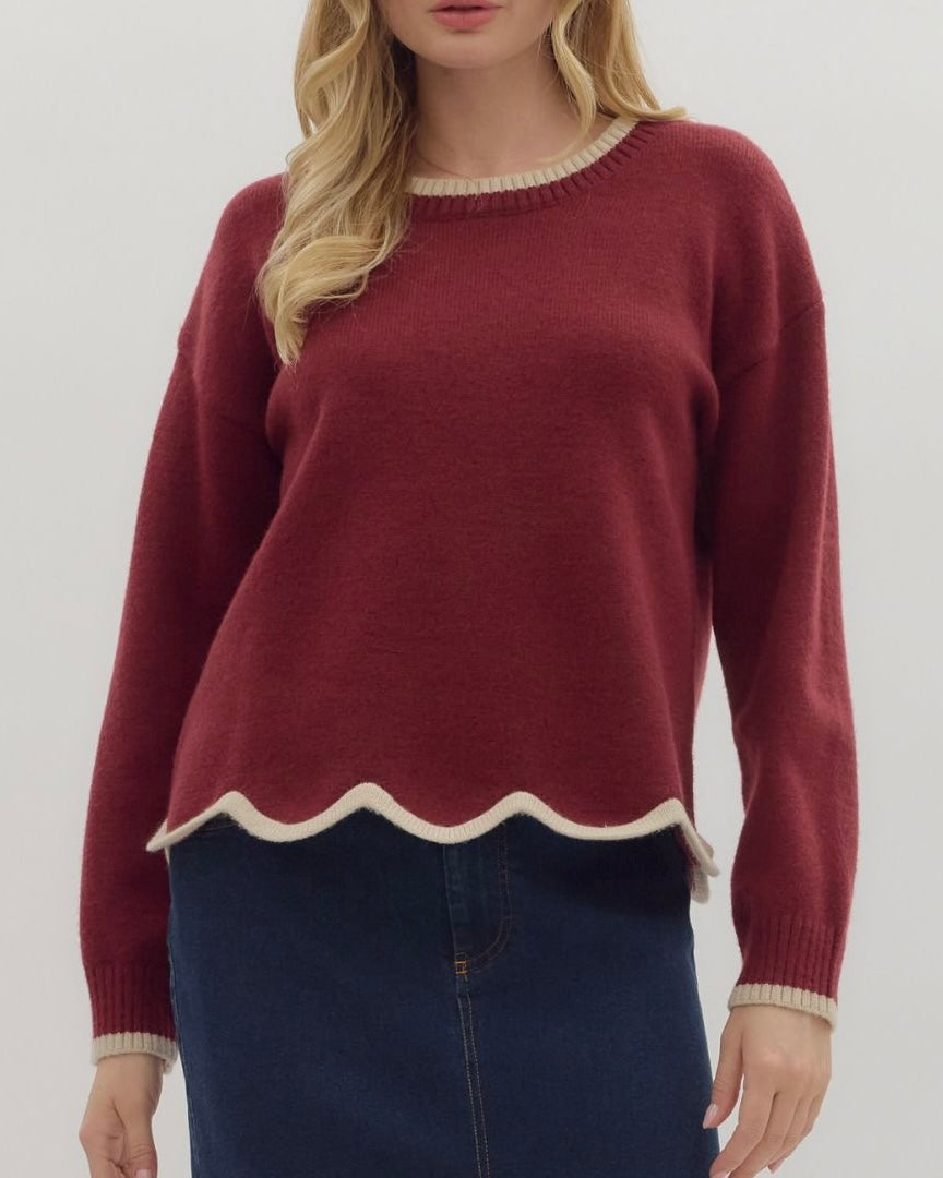Maroon sweater with scalloped hem worn by a person on a white background