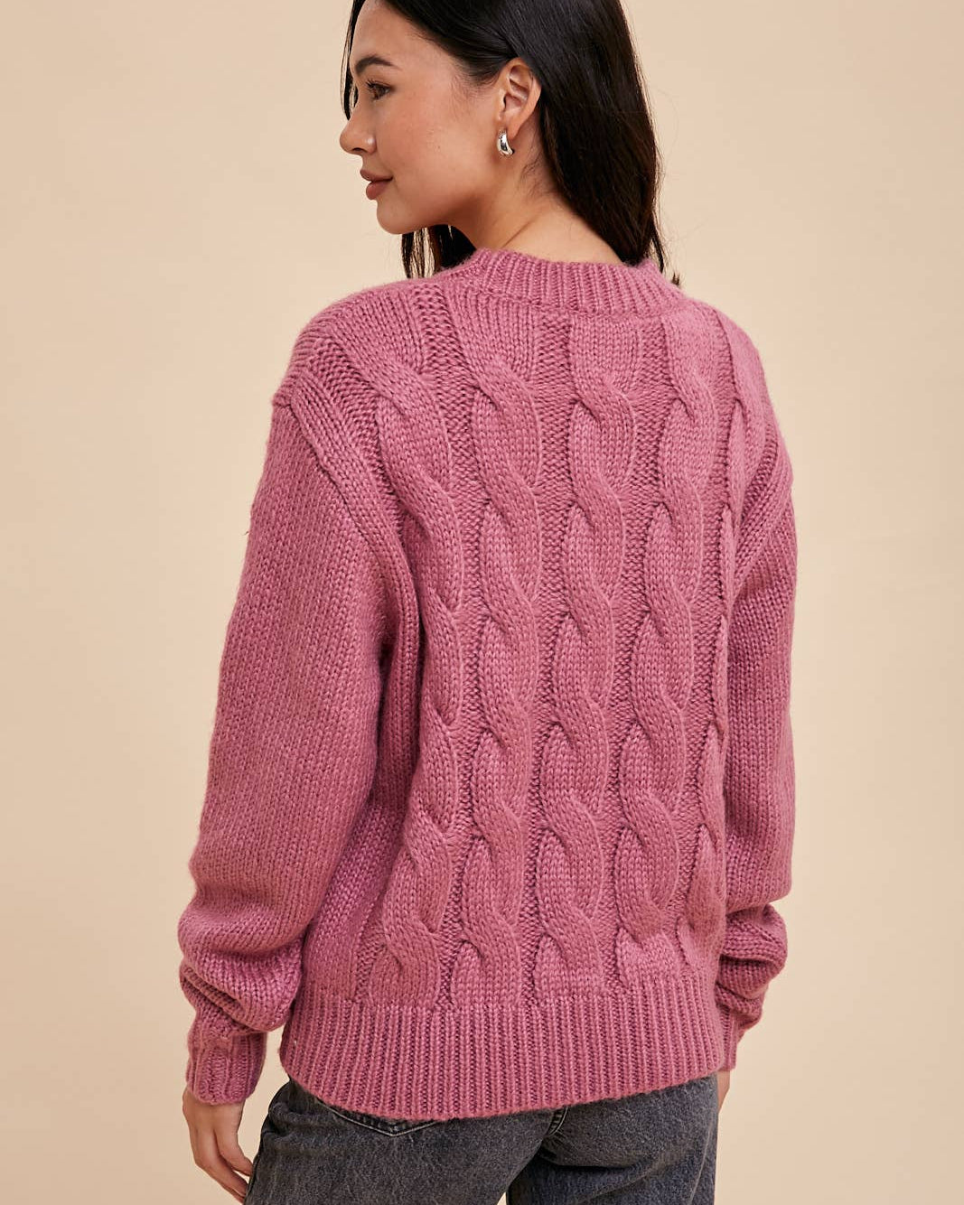 Woman wearing a pink knitted sweater on a beige background