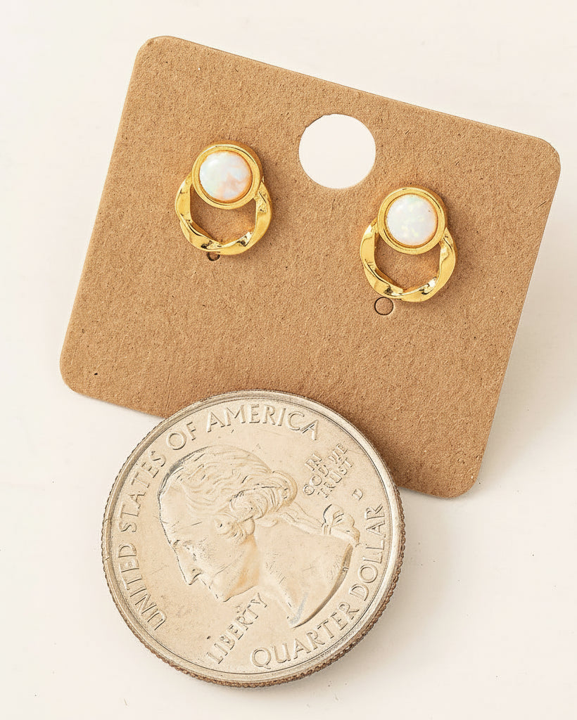 Gold earrings on a display card with a quarter coin for size comparison.