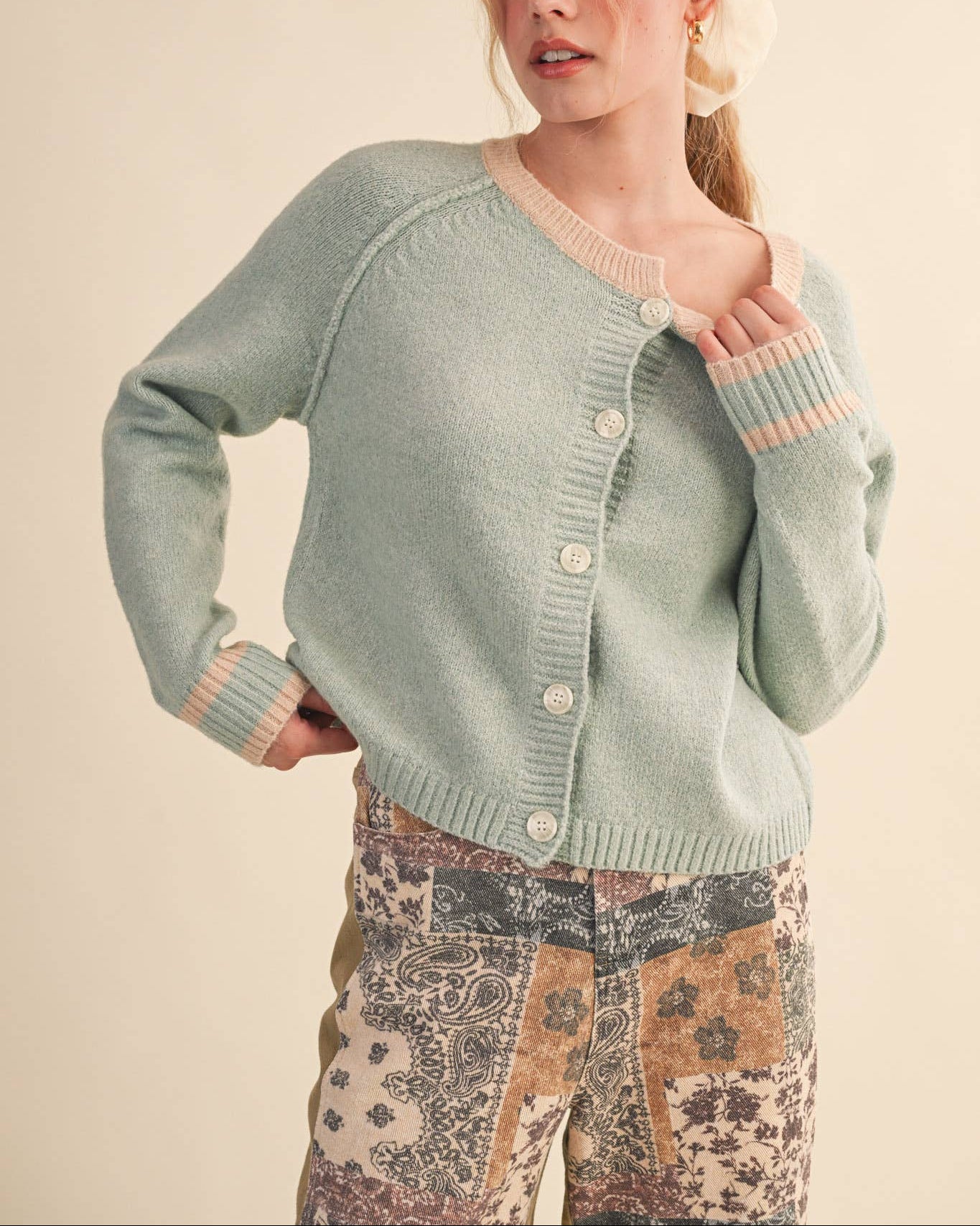 Woman wearing a light green cardigan with a neutral background