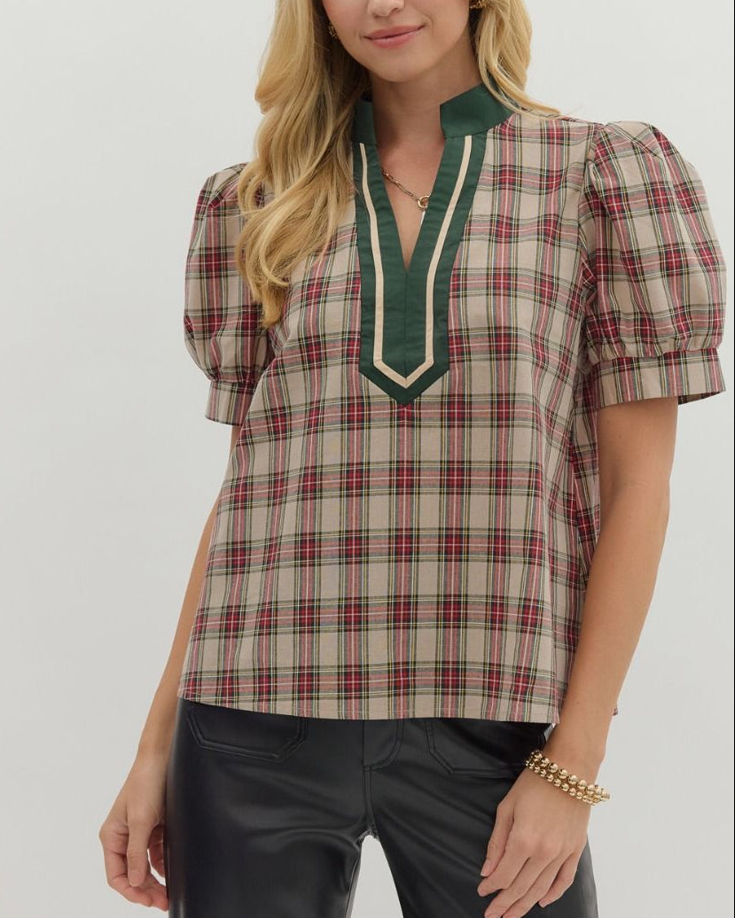 Woman wearing a plaid blouse with green trim and black pants on a white background