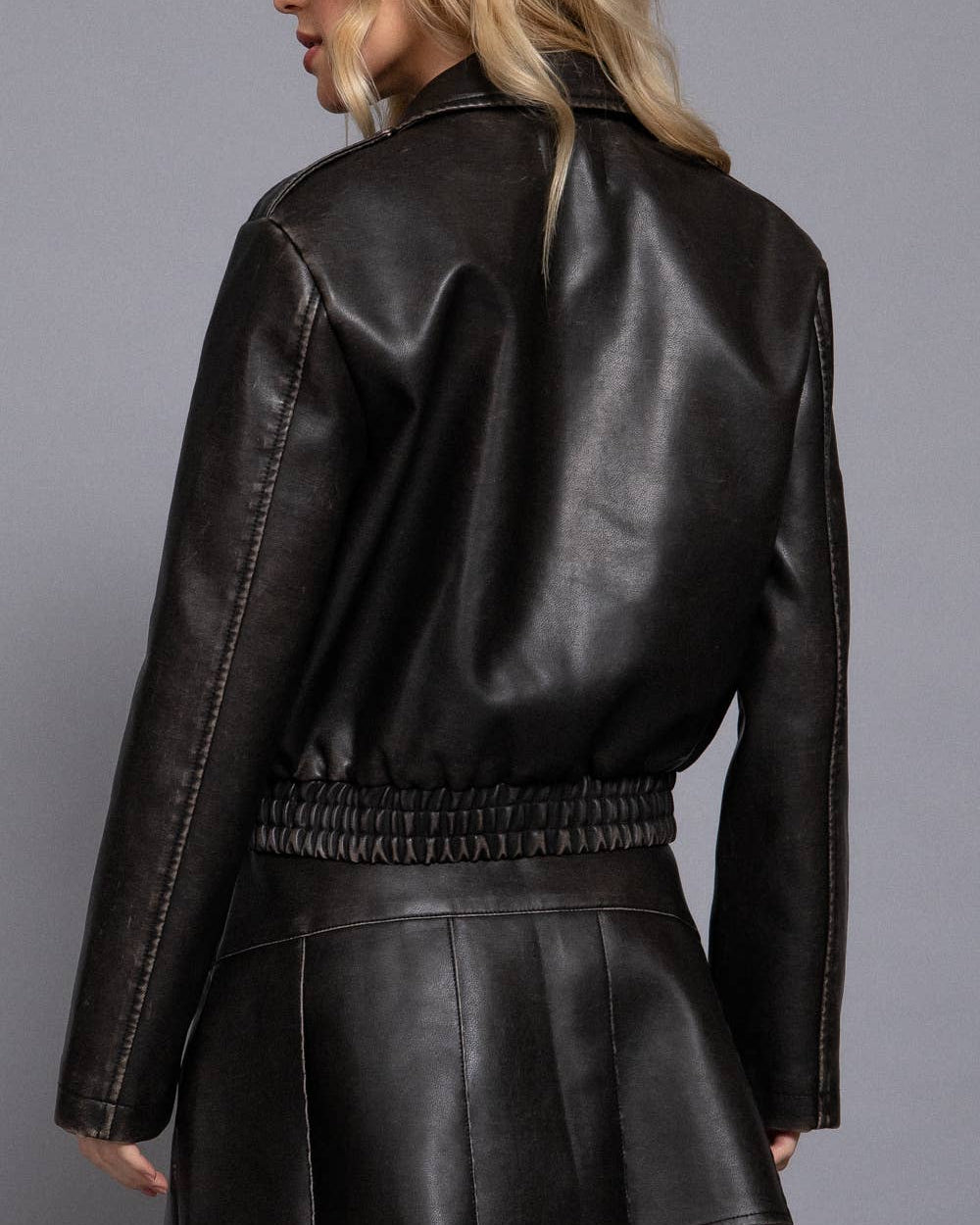 Black leather jacket worn by a person on a gray background