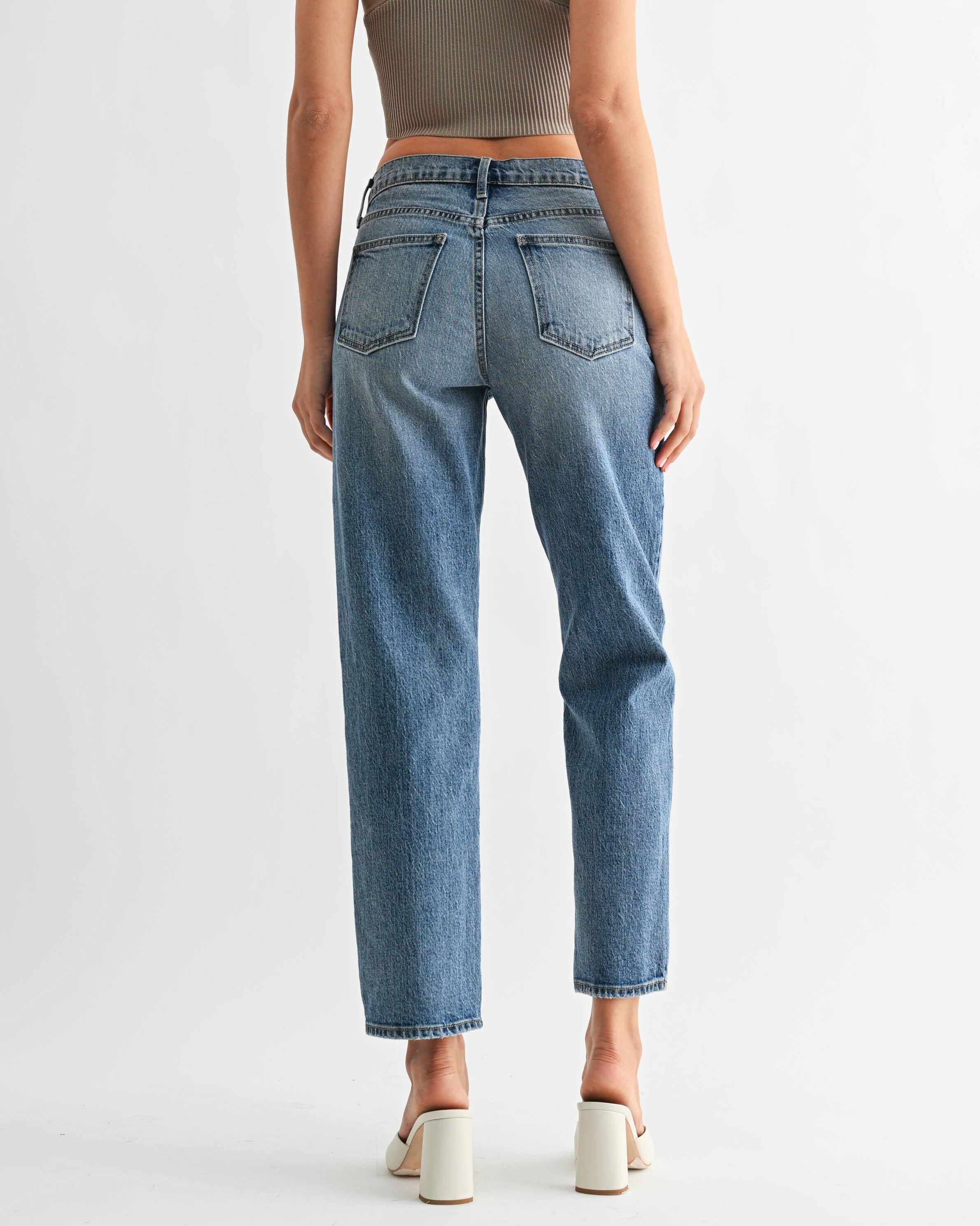 Woman wearing a green crop top and blue jeans on a white background