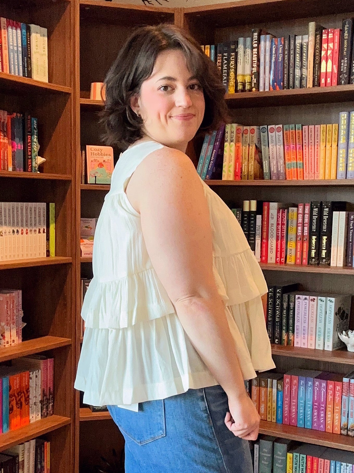 Woman standing in front of a bookshelf filled with books.