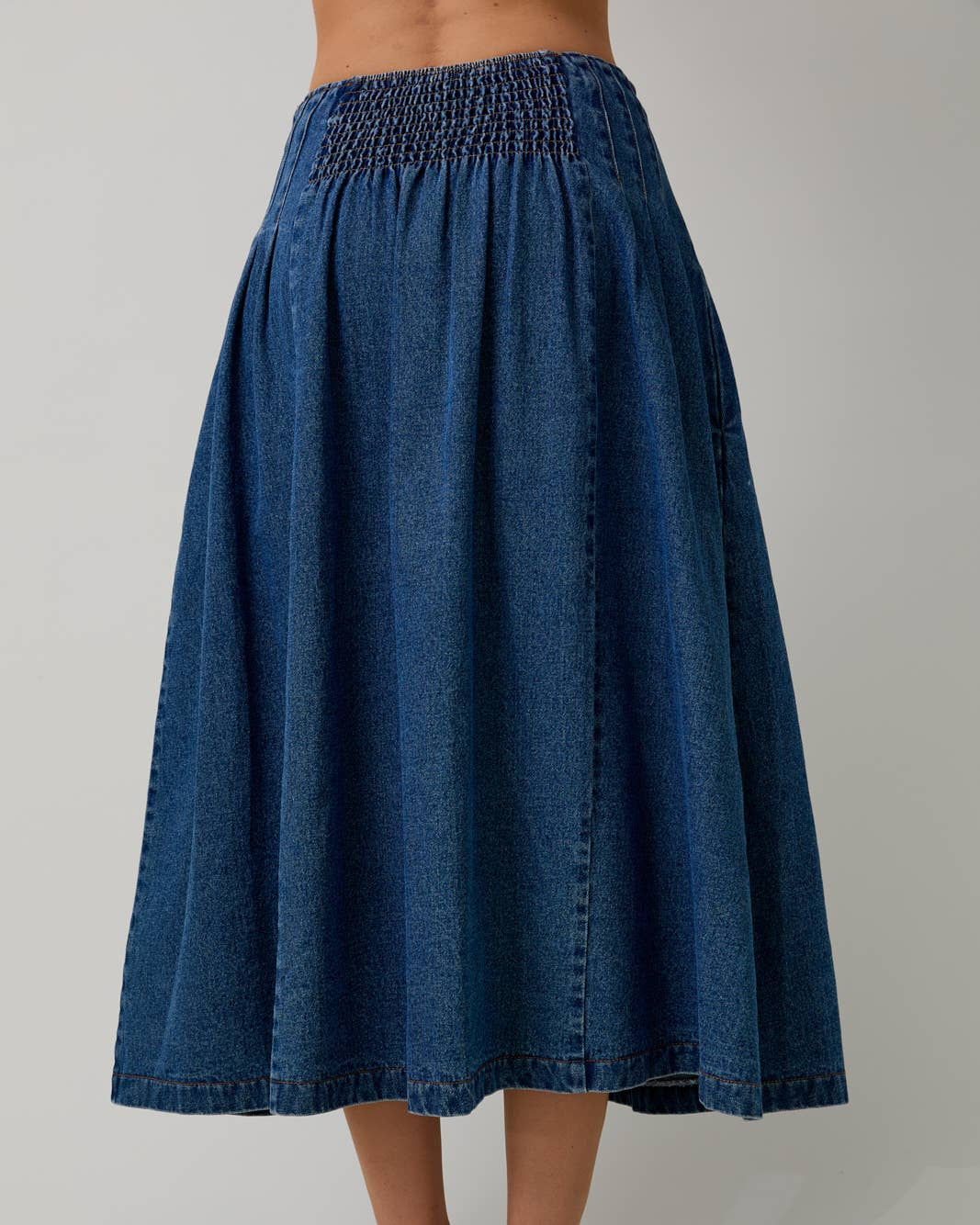 Blue denim skirt worn by a person on a plain background