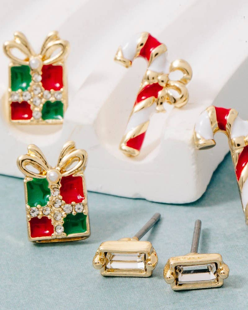 Set of festive earrings including gift box, candy cane, and bow designs on a light blue background.