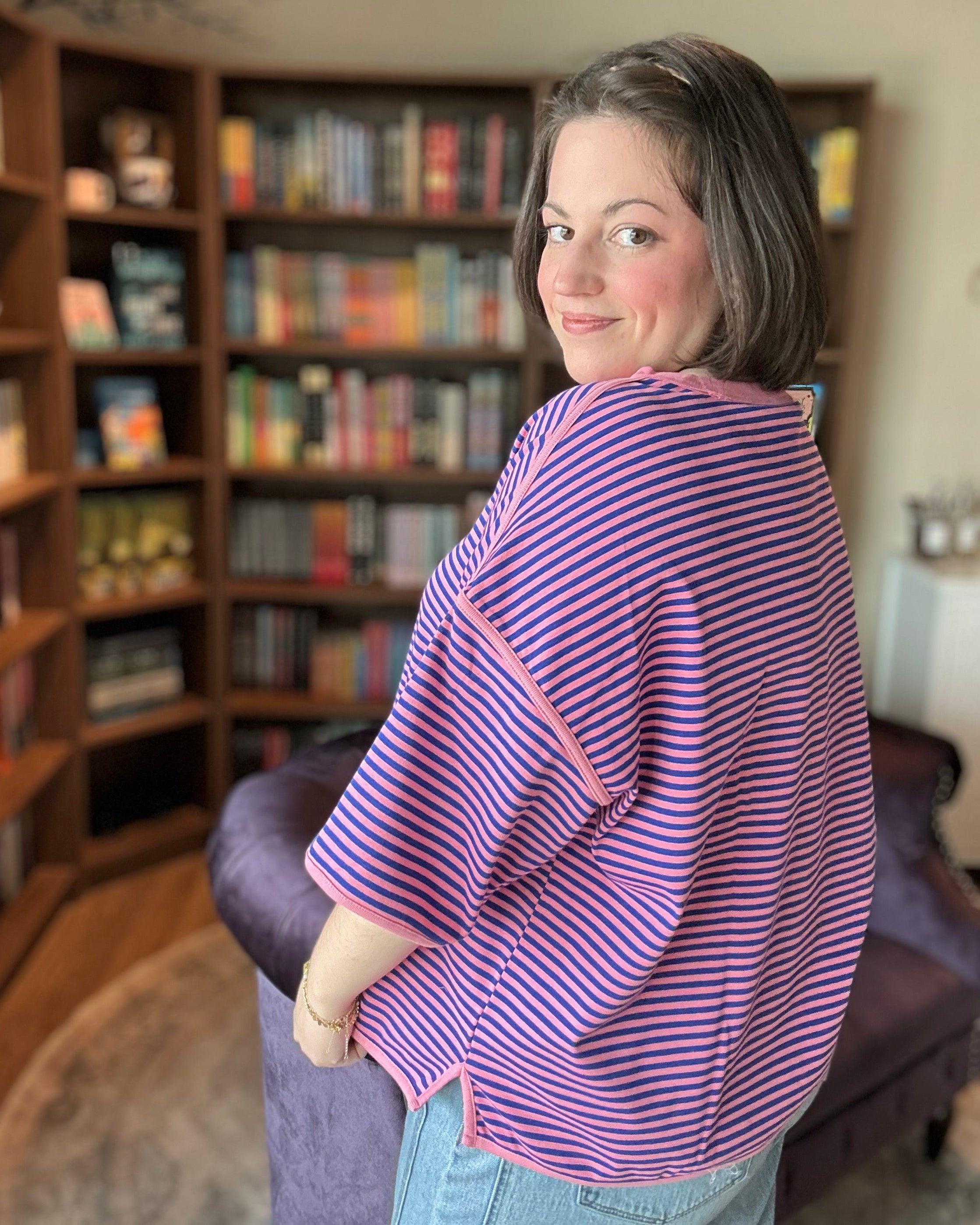 Woman wearing a purple striped shirt in a room with bookshelves.