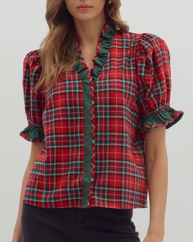 Woman wearing a red plaid blouse with green trim on a white background