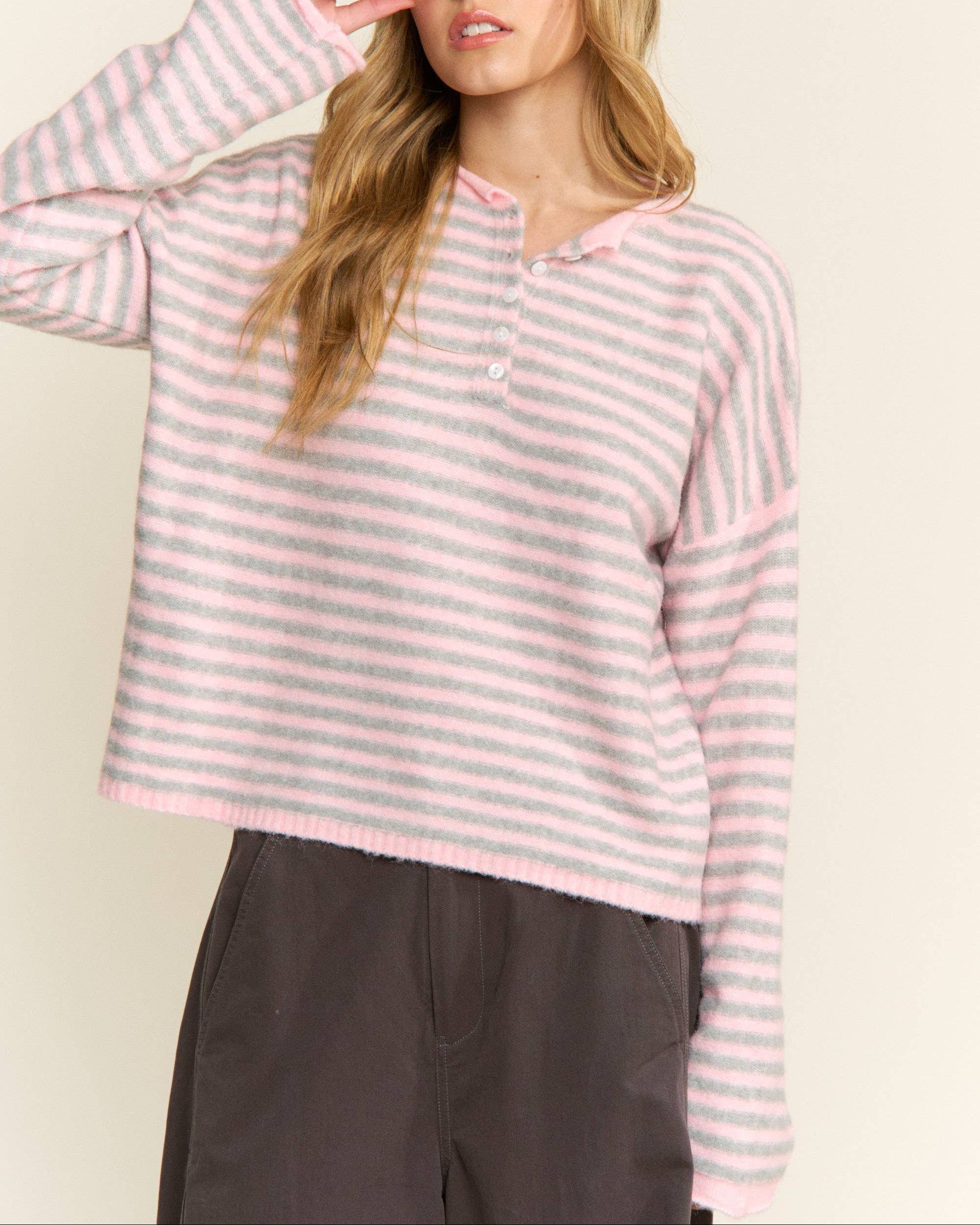 Woman wearing a pink and white striped sweater against a plain background