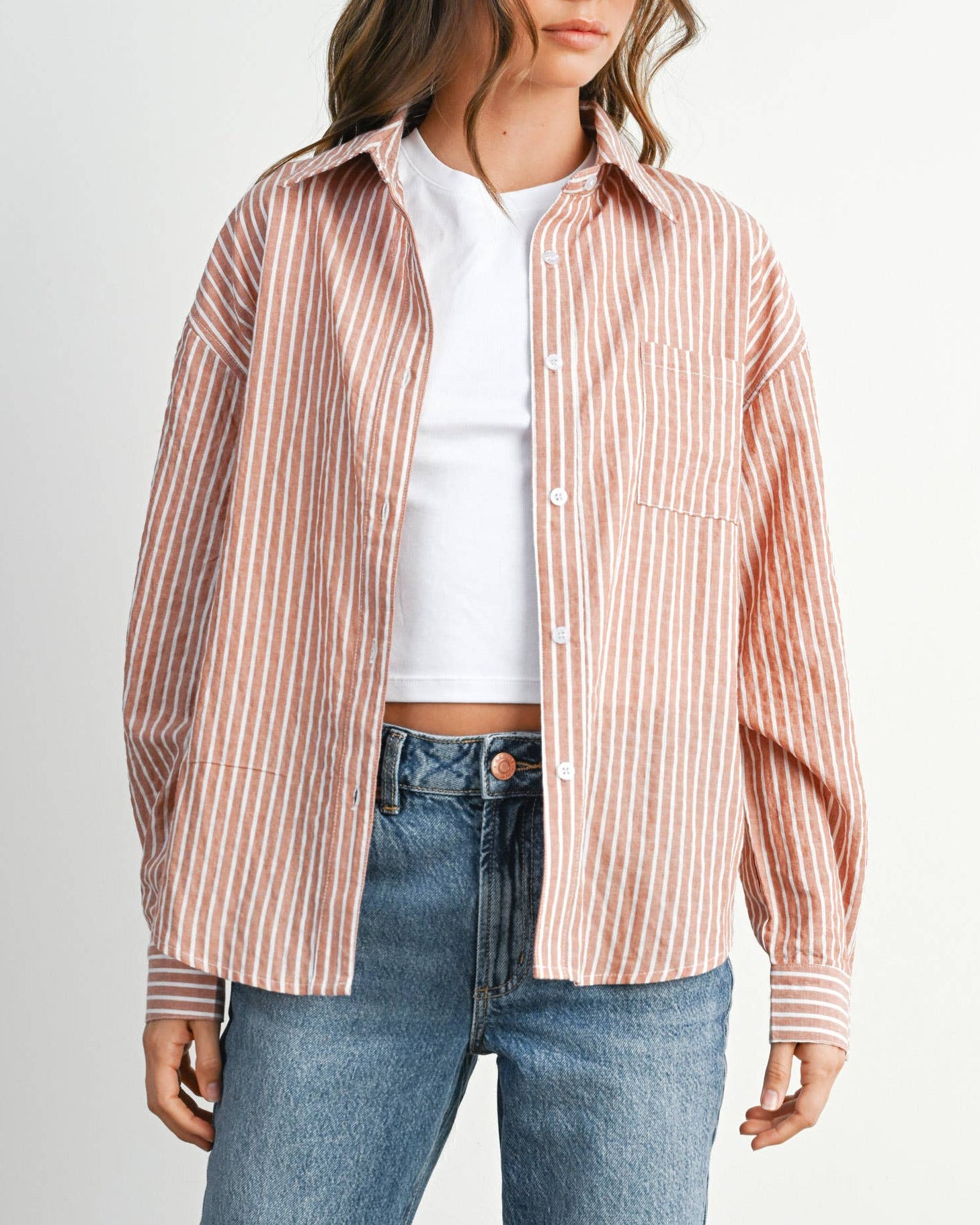 Woman wearing a striped shirt and jeans against a white background