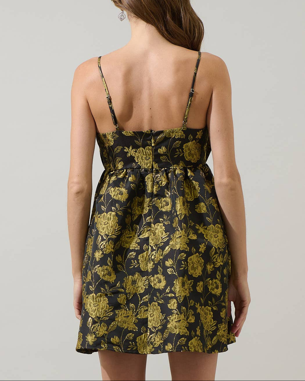 Woman wearing a black floral dress with thin straps on a plain background