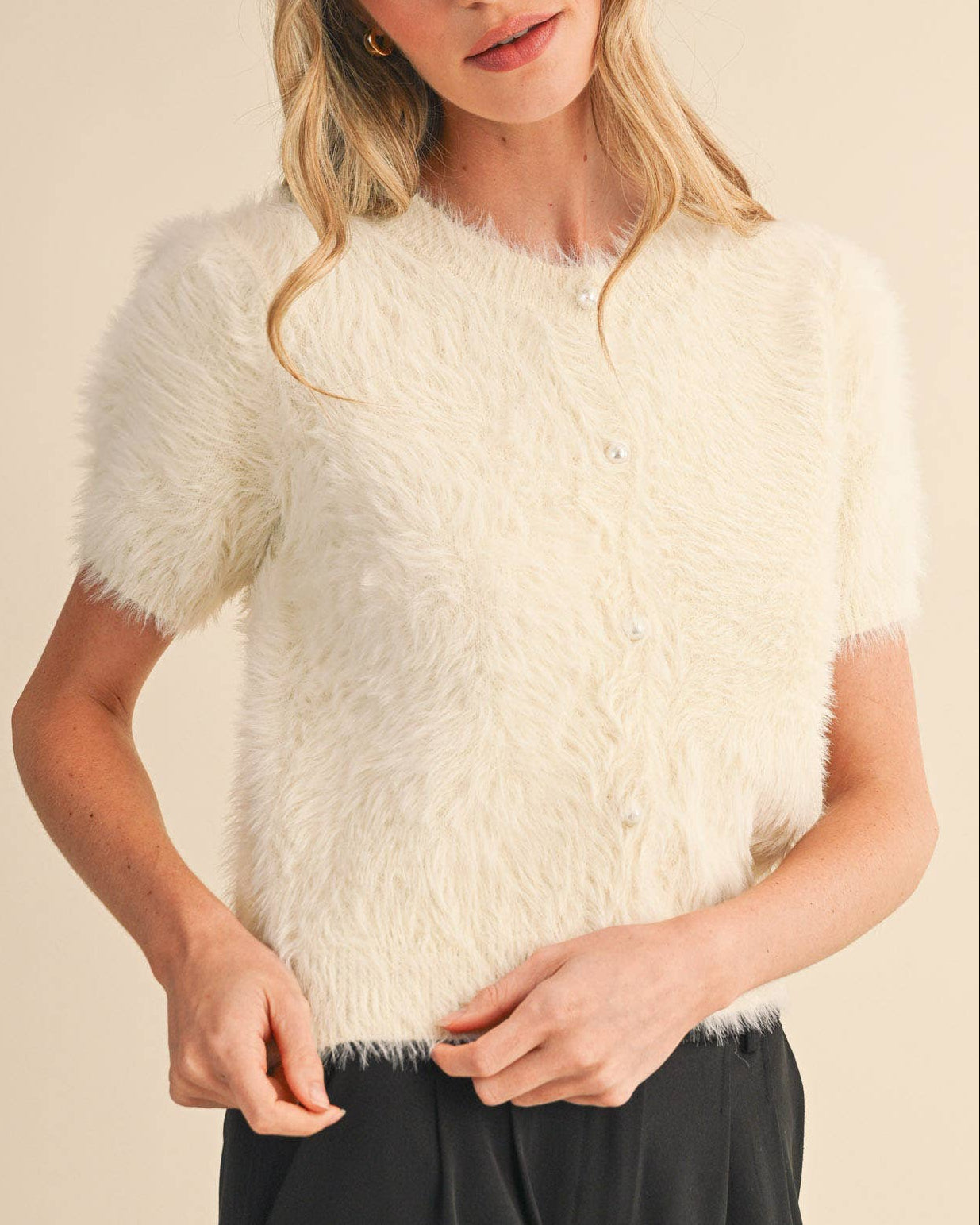 Woman wearing a white fluffy cardigan against a beige background