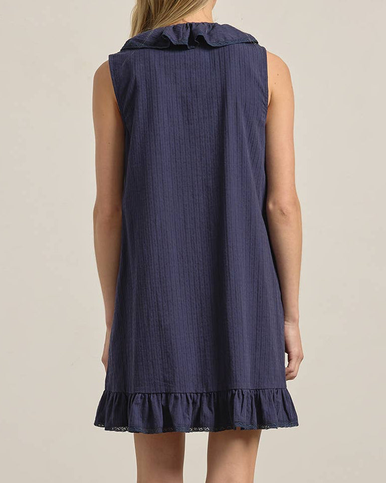 Woman wearing a navy dress with ruffled hem on a plain background