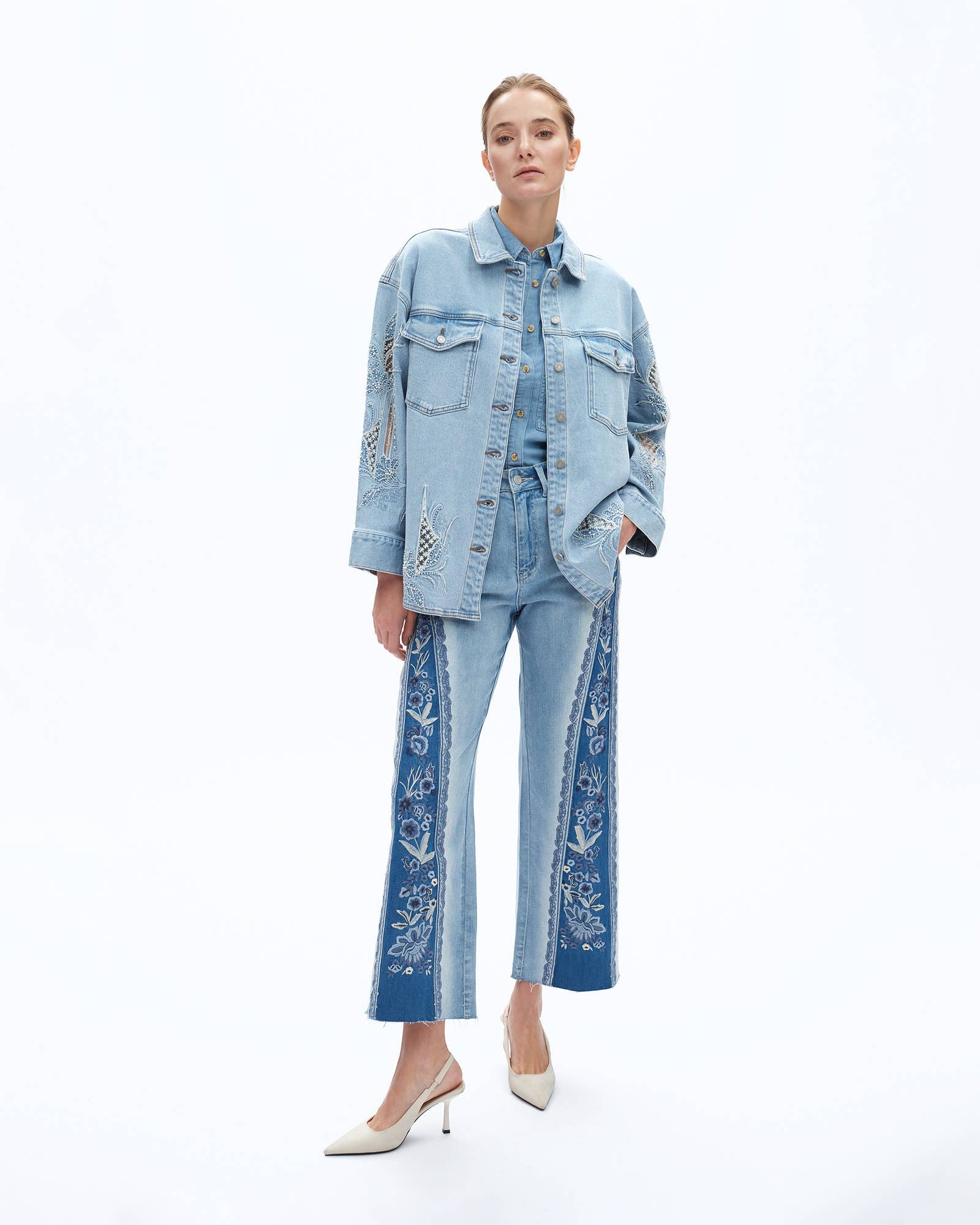Woman wearing a denim outfit with embroidered details on a white background