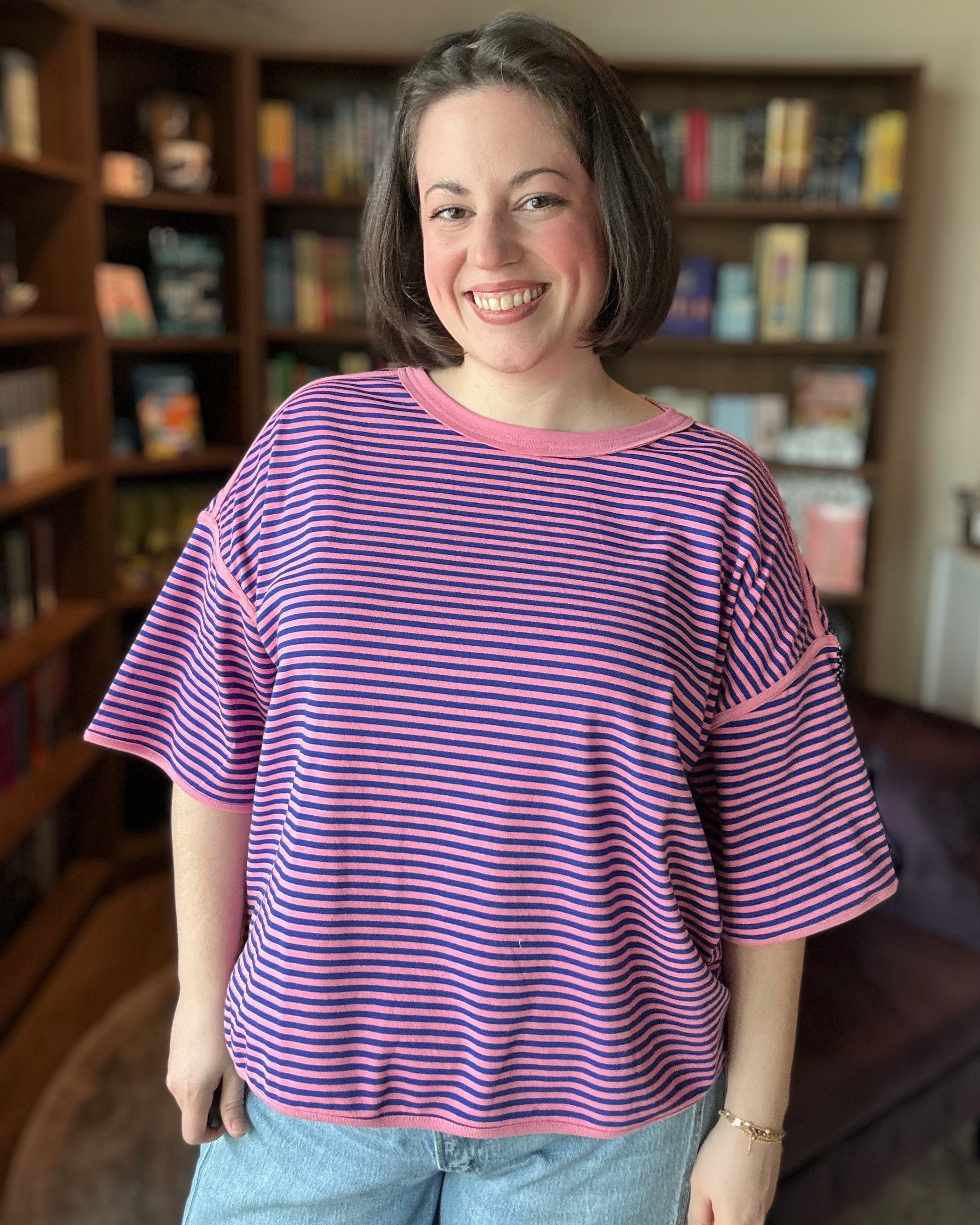 Woman wearing a royal blue and pink striped shirt in a room with bookshelves.
