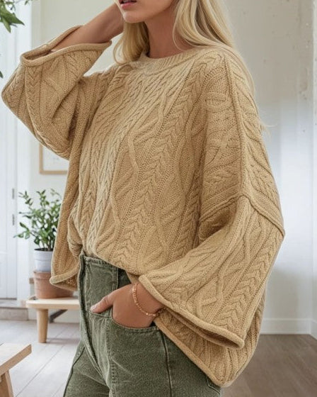 Woman wearing a beige cable knit sweater in a home setting