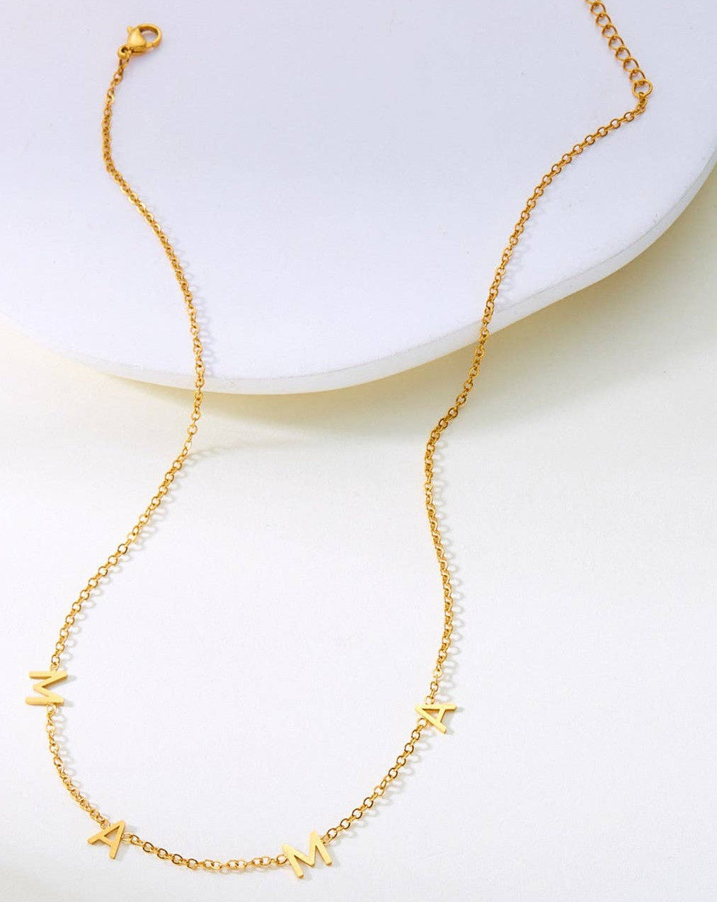 Gold necklace with mama charms on a white plate