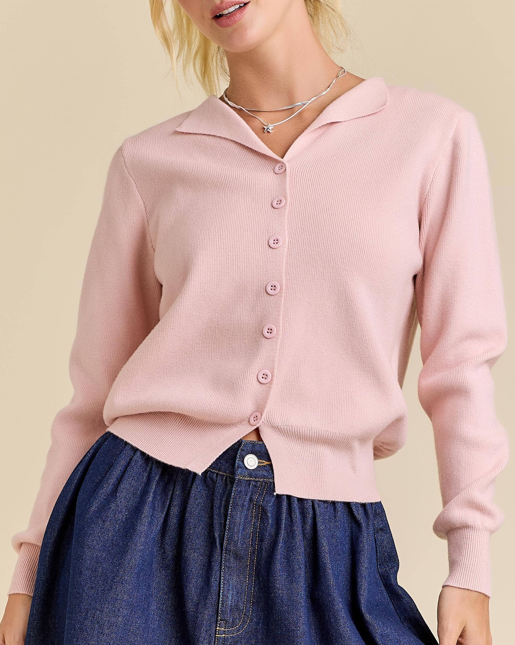 Woman wearing a pink cardigan over a blue skirt on a beige background