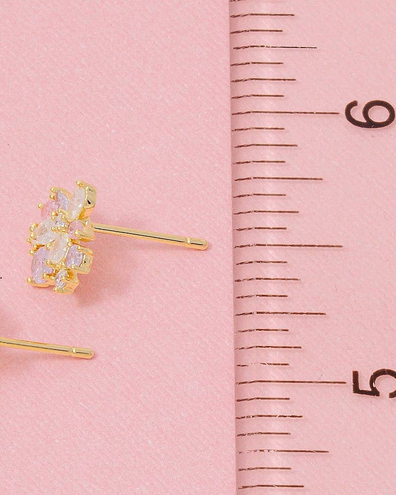 Gold earrings on a pink background with a ruler for scale