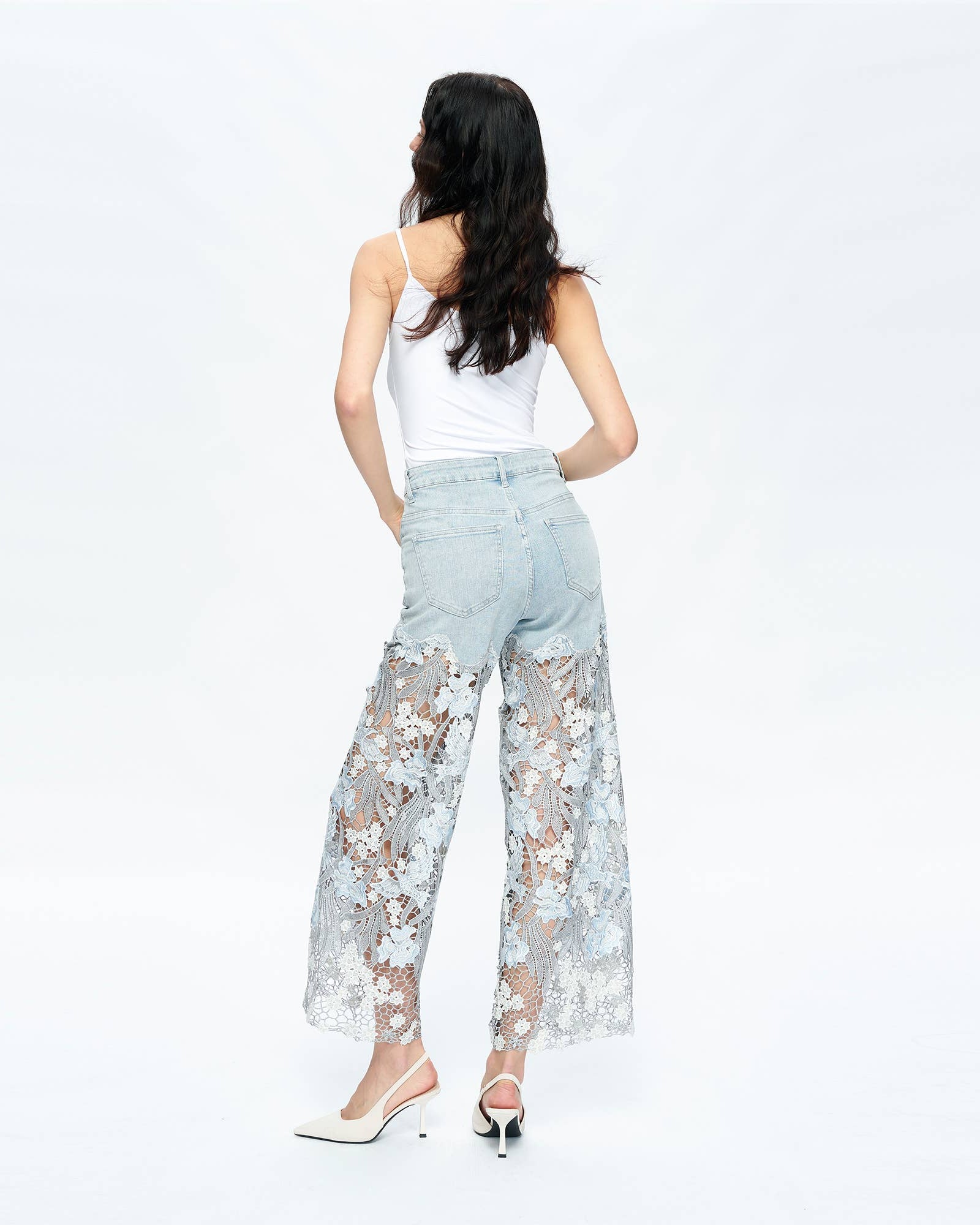 Woman wearing light blue lace pants and a white top on a white background