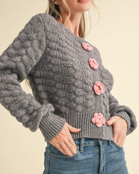 Woman wearing a gray knitted sweater with pink buttons on a beige background