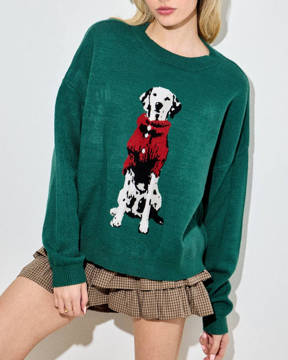 Woman wearing a green sweater with a dalmatian dog design on a white background