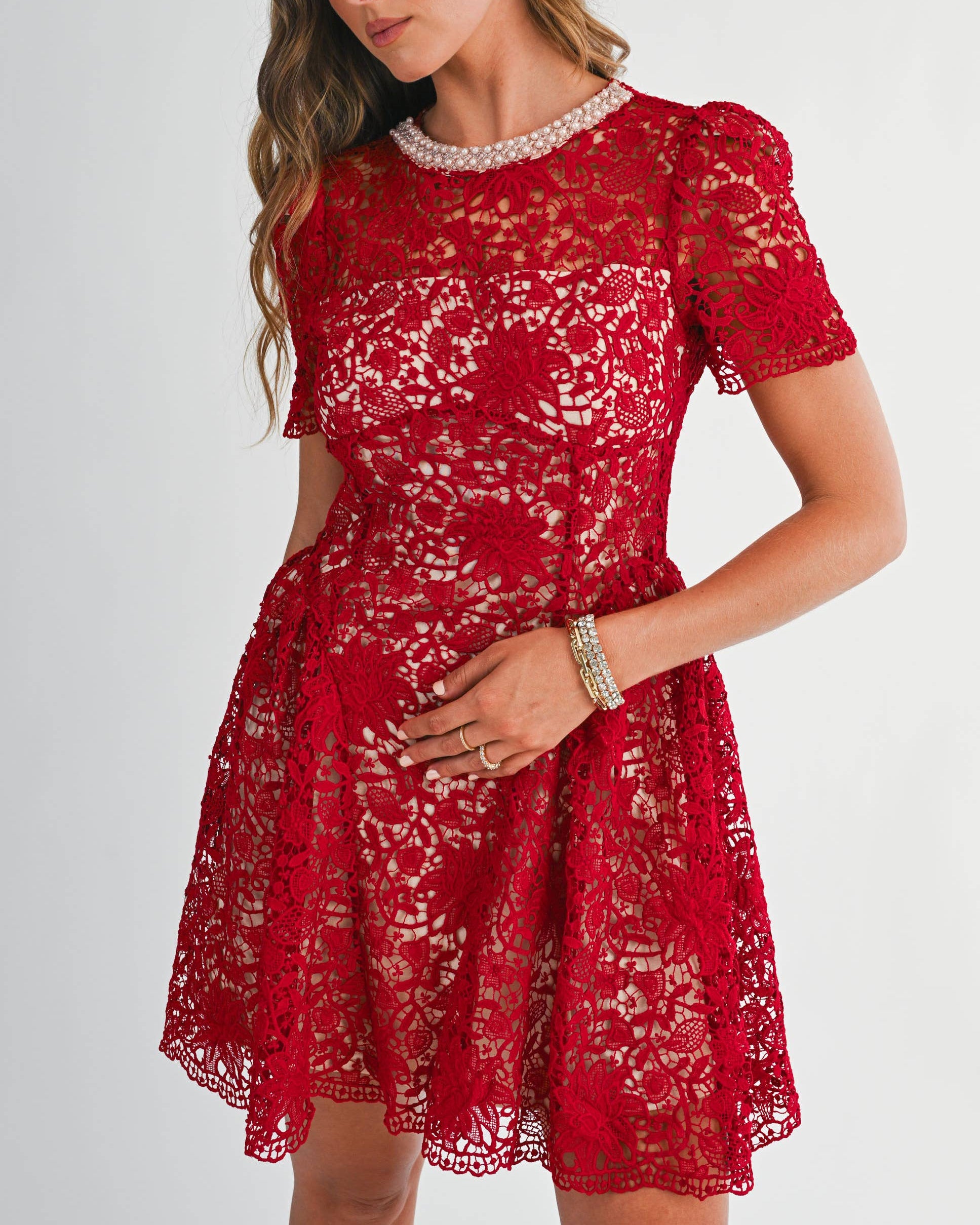 Woman wearing a red lace dress with a white background