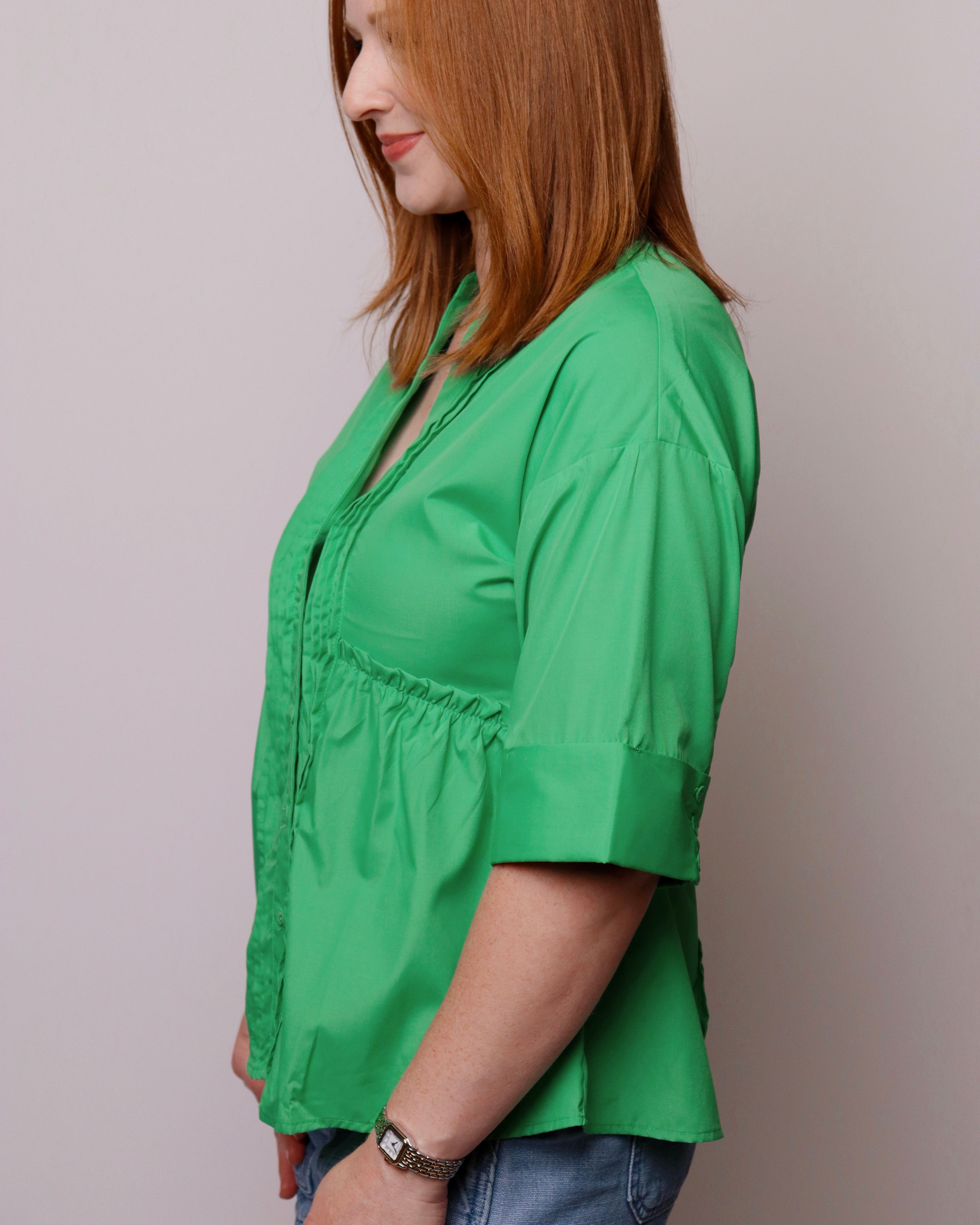 Person wearing a green blouse against a plain background