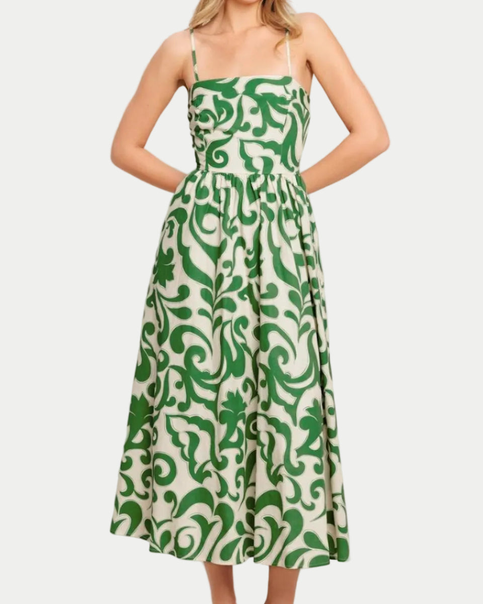 Green printed woven midi dress with adjustable straps, elastic on back, and pockets.  On a model with a neutral backgrouns.  Front view