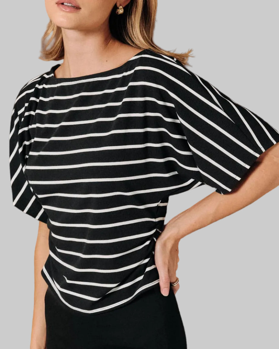 A model wearing a black and white horizontally striped short-sleeve top with dolman sleeves on a neutral background