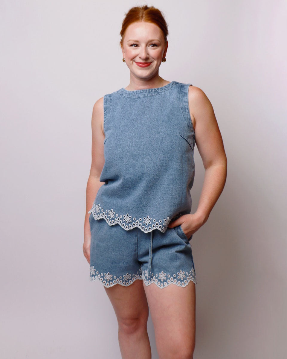 Woman wearing a blue denim outfit with lace trim on a plain background