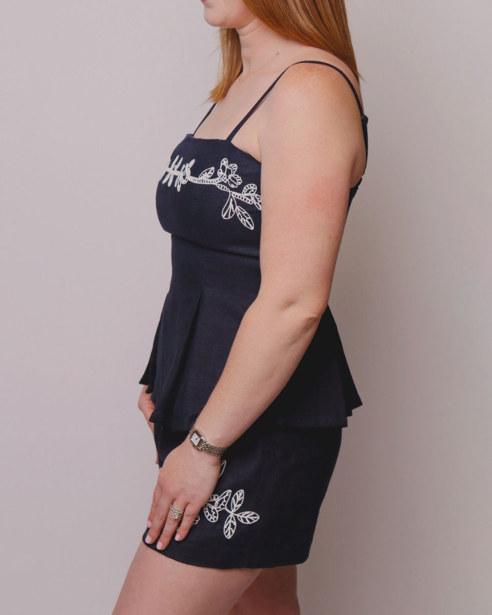 Navy blue dress with white floral embroidery on a plain background