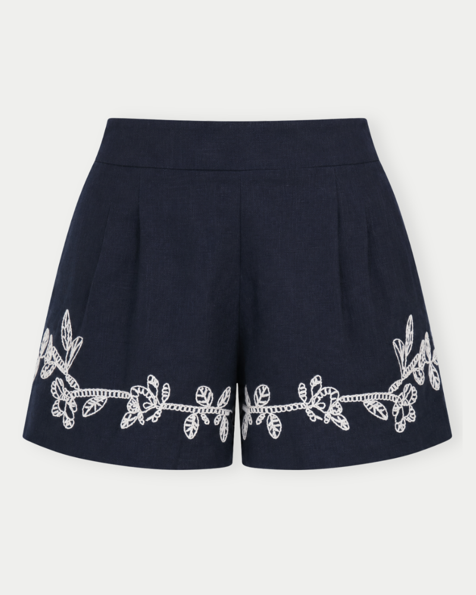 Navy shorts with white floral embroidery on a light gray background
