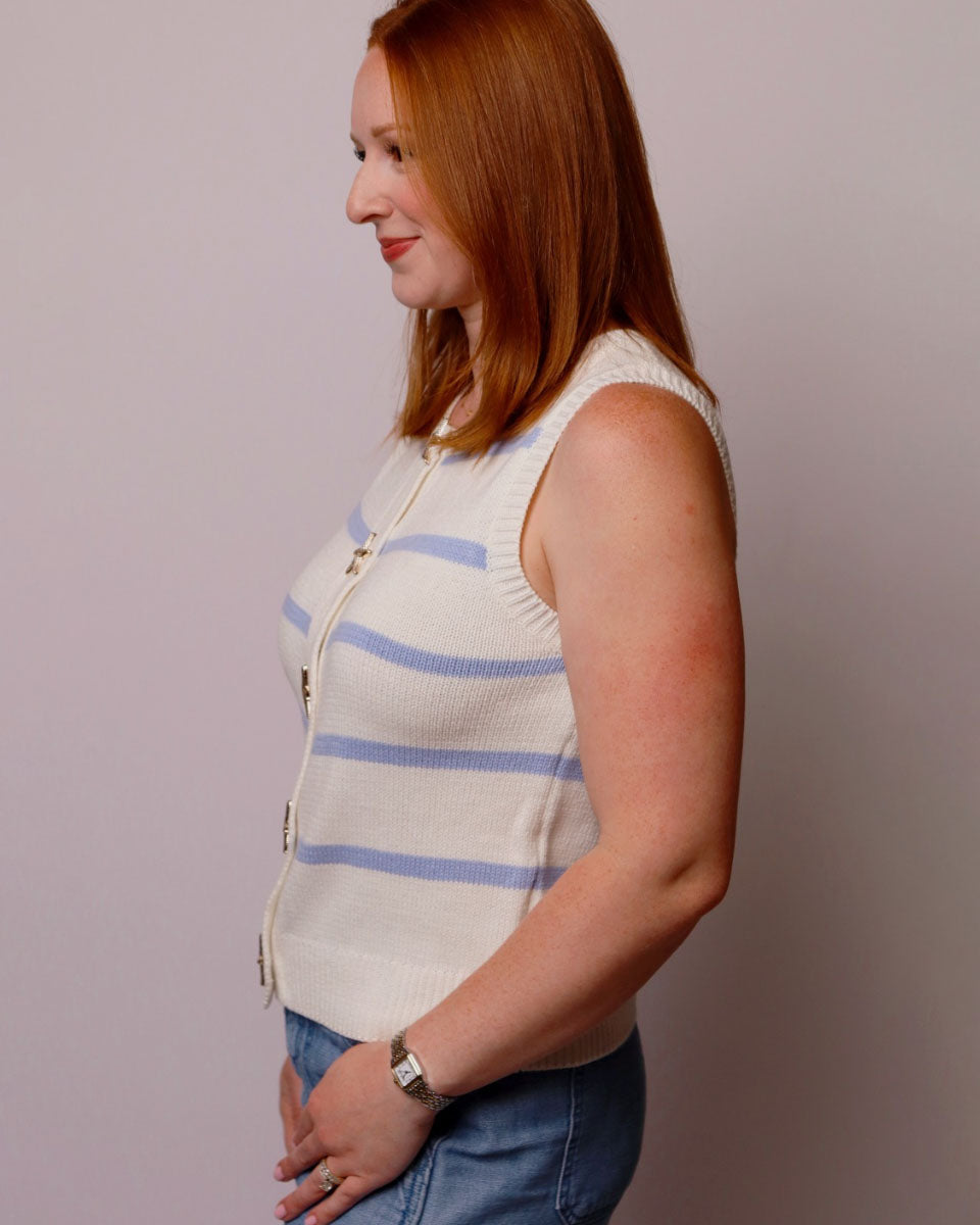 Woman wearing a white sleeveless striped shirt against a plain background