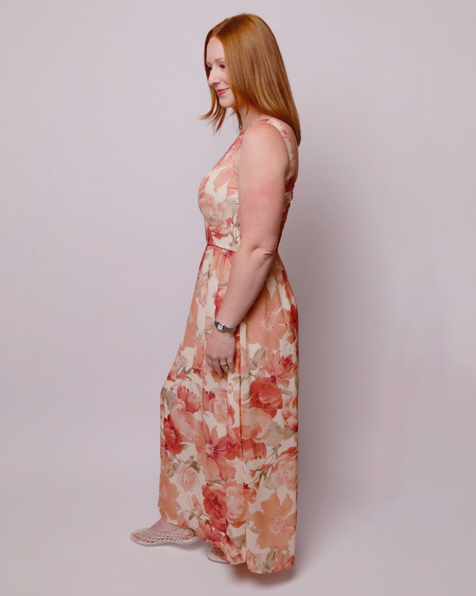 Woman wearing a floral dress against a plain background. Side view