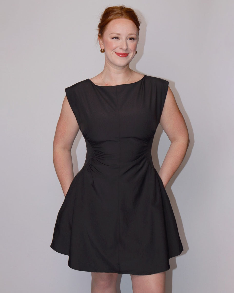 Woman wearing a black dress against a plain background