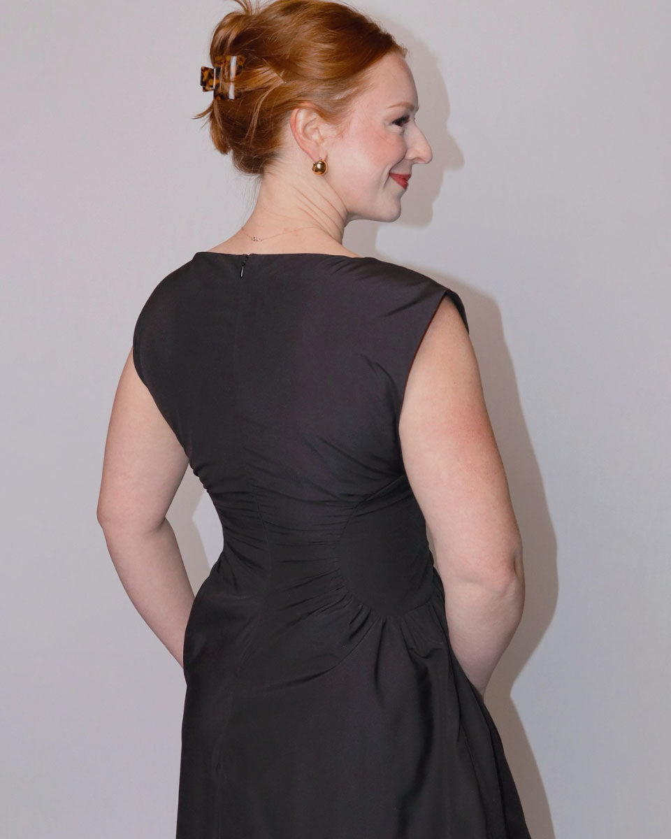 Woman wearing a black dress against a plain background