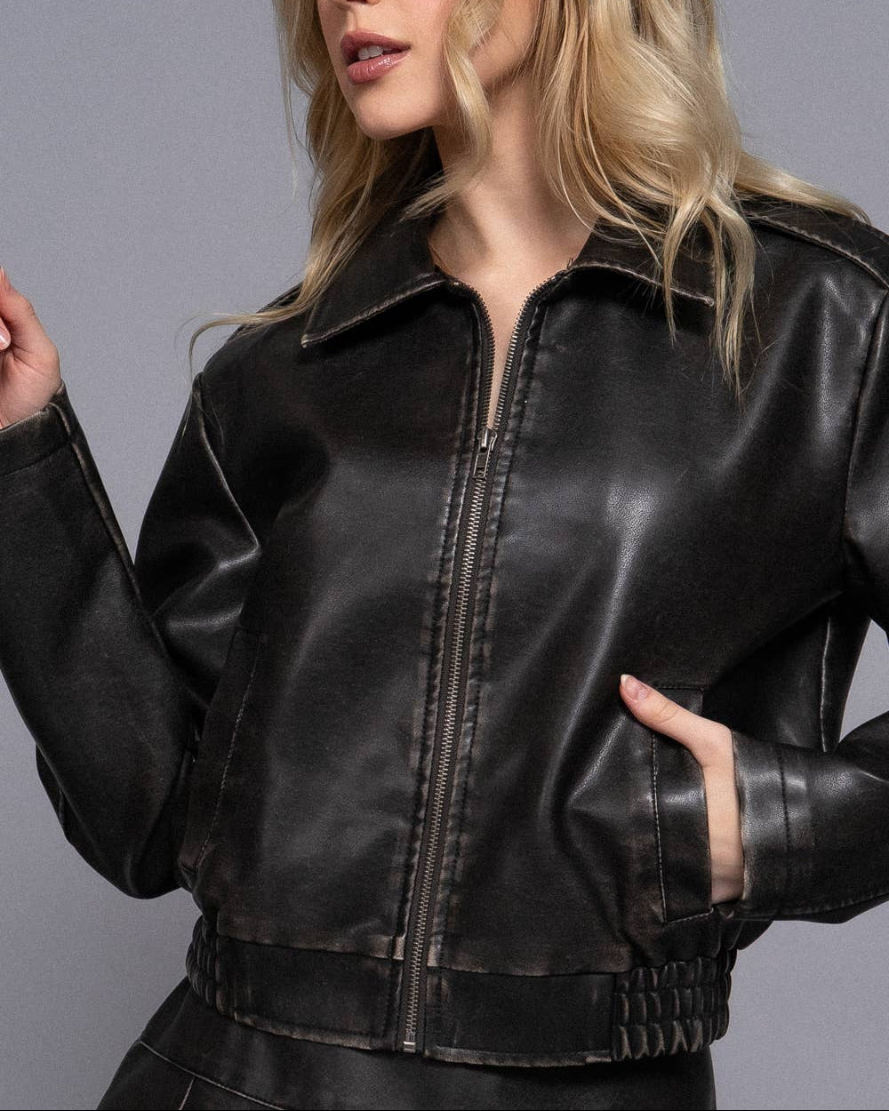 Woman wearing a black leather jacket against a gray background