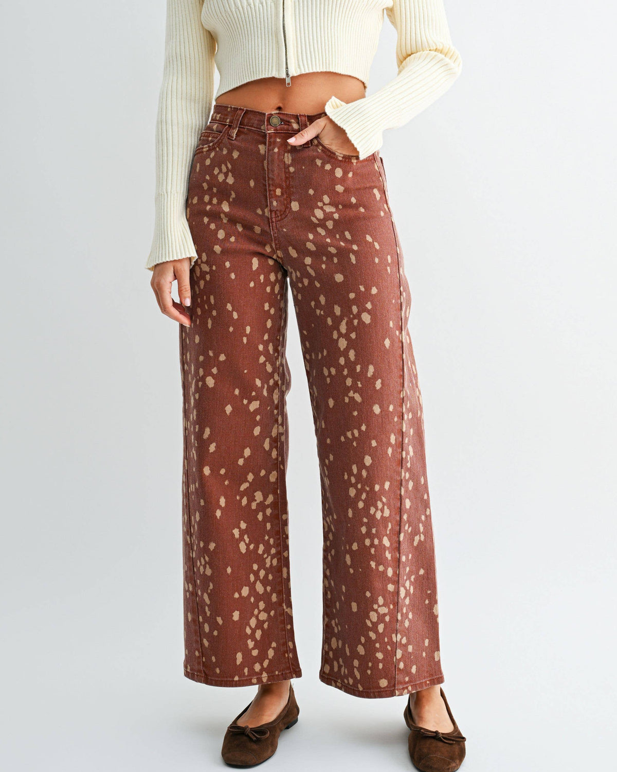 A woman modeling a cream ribbed zip-front crop sweater and rust-brown wide-leg pants with a small beige floral pattern, paired with brown flats, against a light gray studio background. Bambi Deer Print Seamed Slim Wide Leg Jeans | Blackbird Boutique