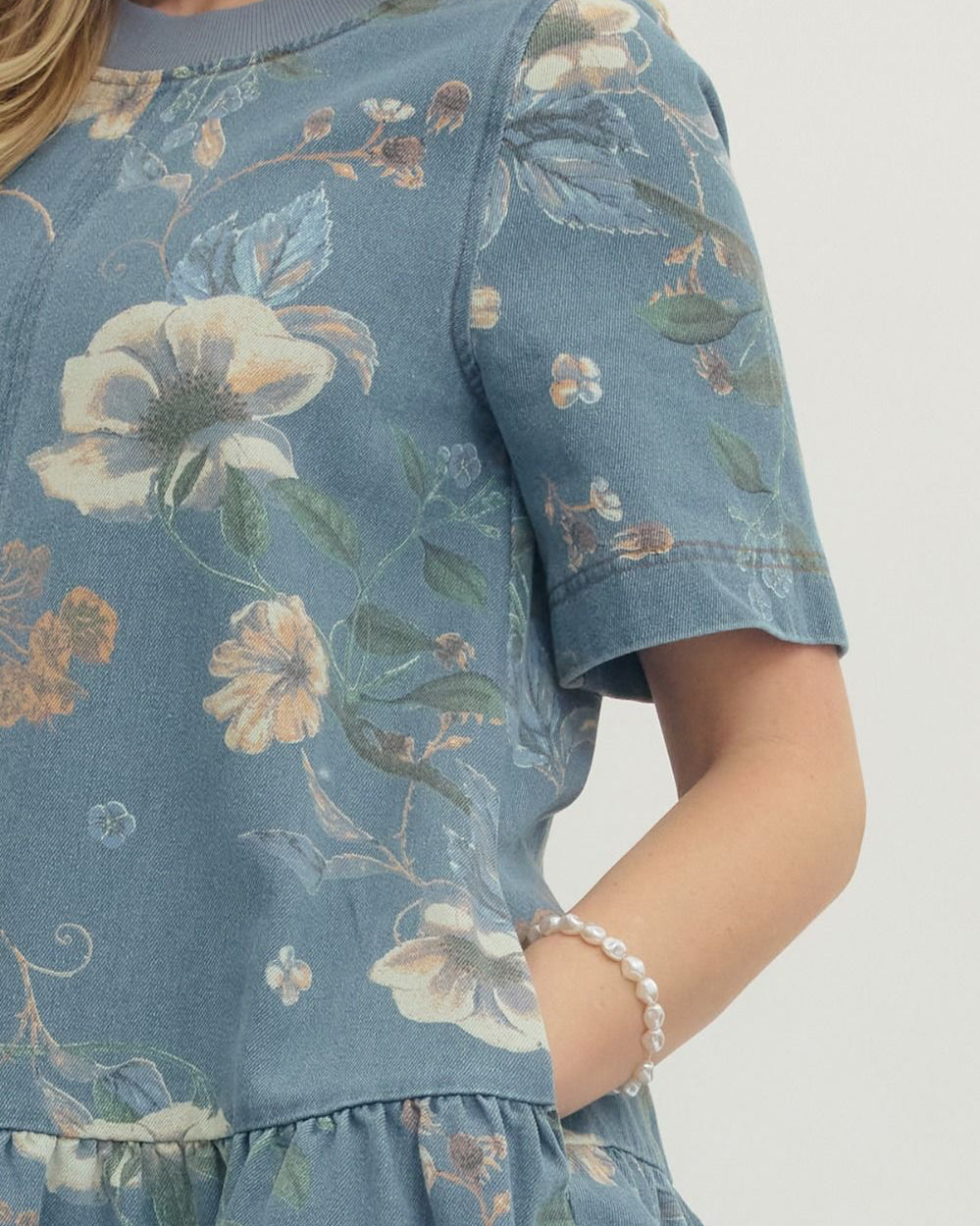 Blue floral dress worn by a person on a white background