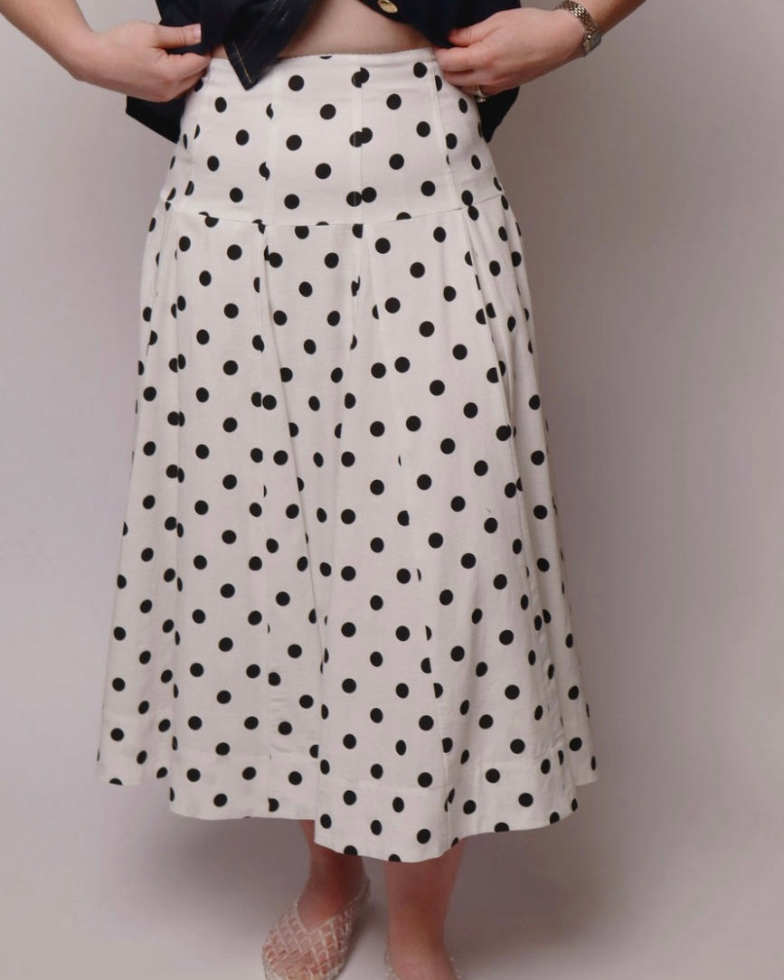 Person wearing a white polka dot skirt on a plain background