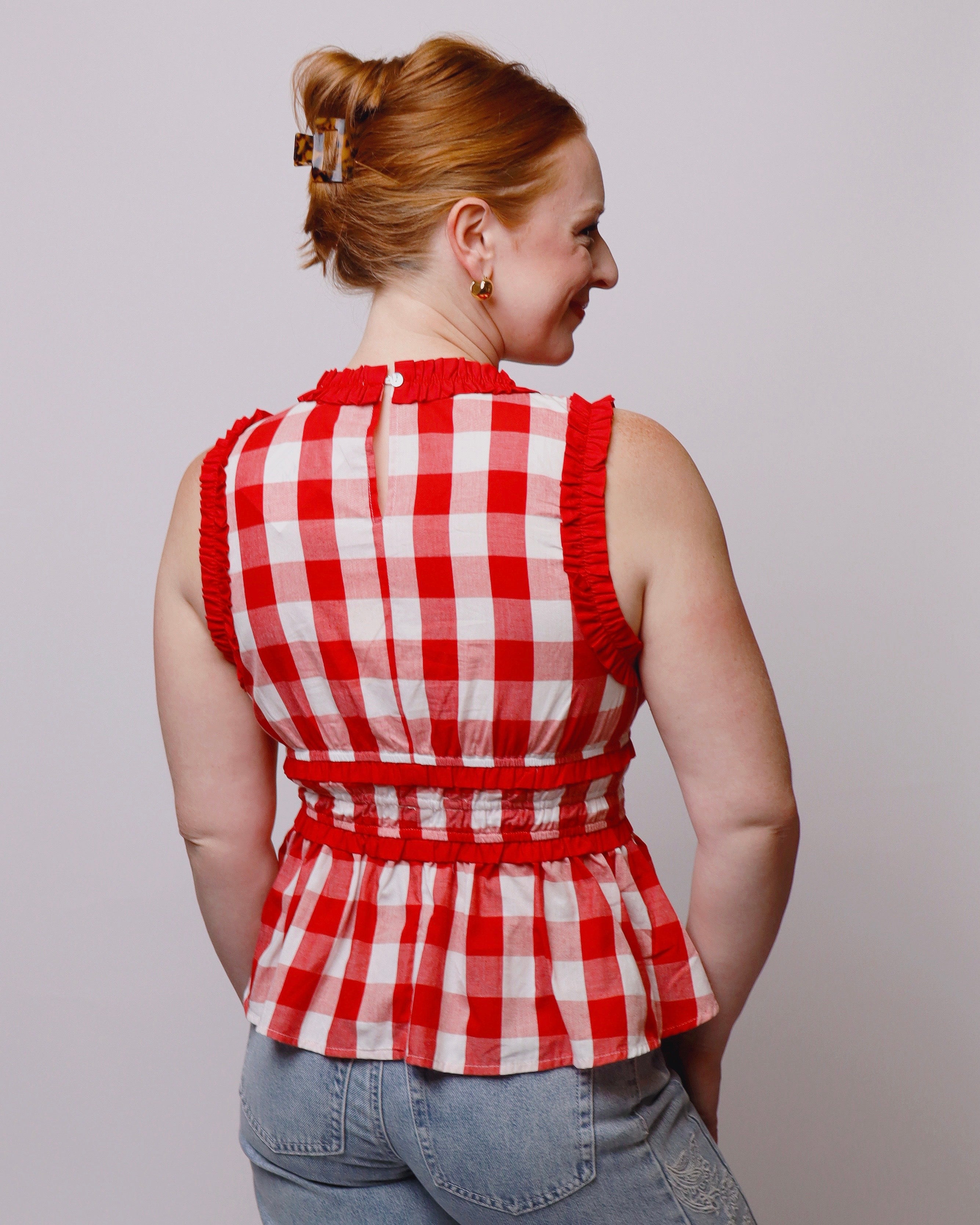 Woman wearing a red and white checkered top against a plain background