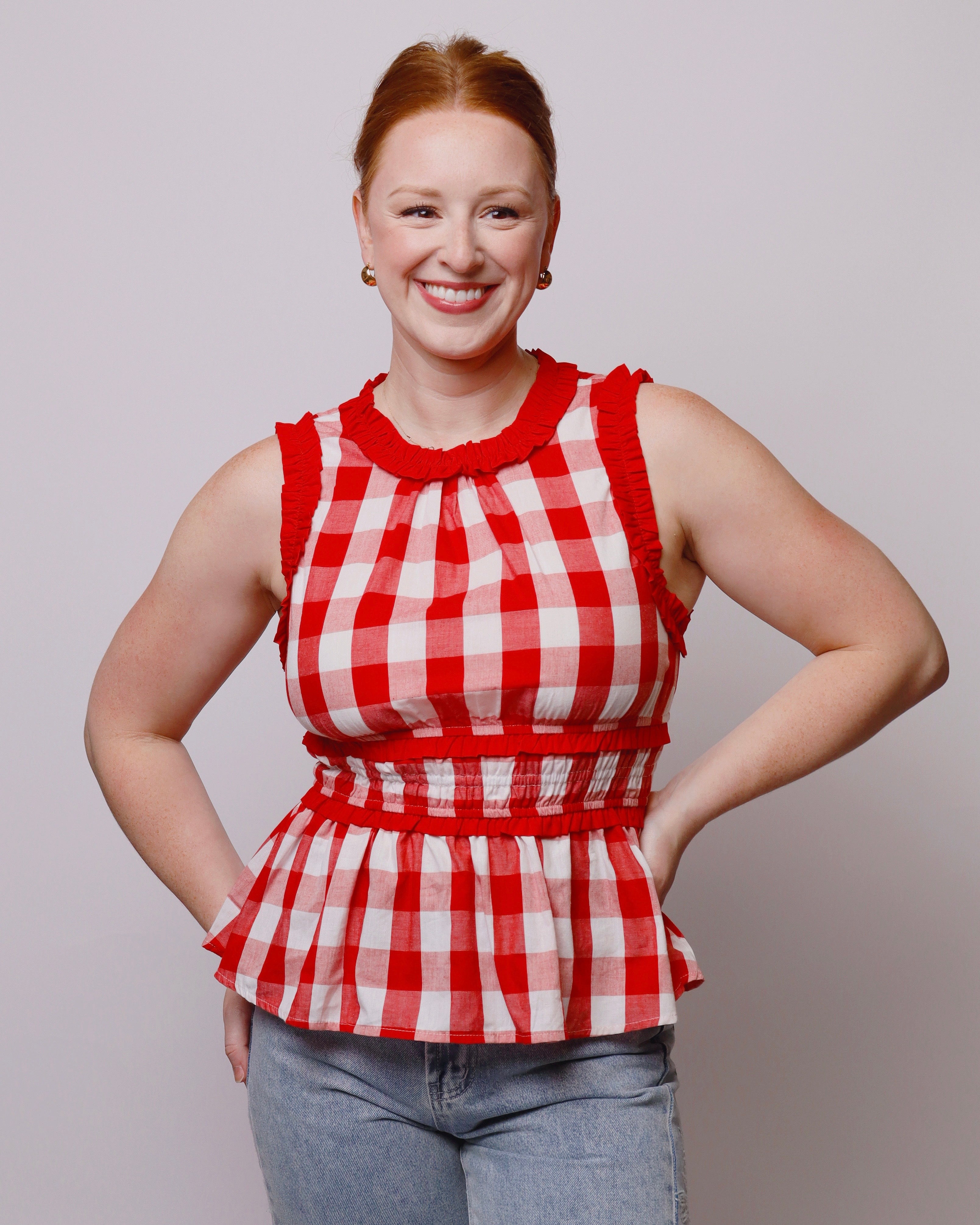 Woman wearing a red and white checkered top against a plain background
